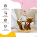 Toddler sitting on brown plush rocking horse toy with wooden base in a nursery room