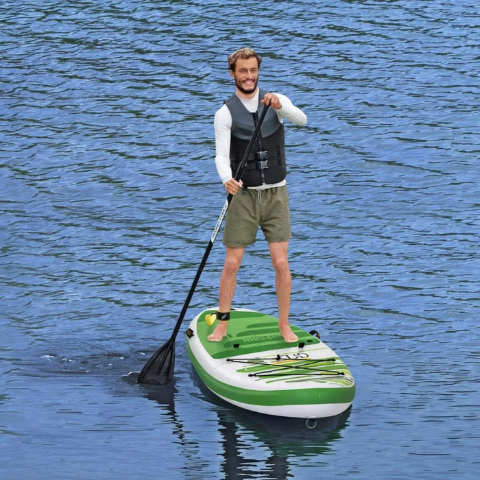 Man paddleboarding on inflatable green and white SUP in calm blue water