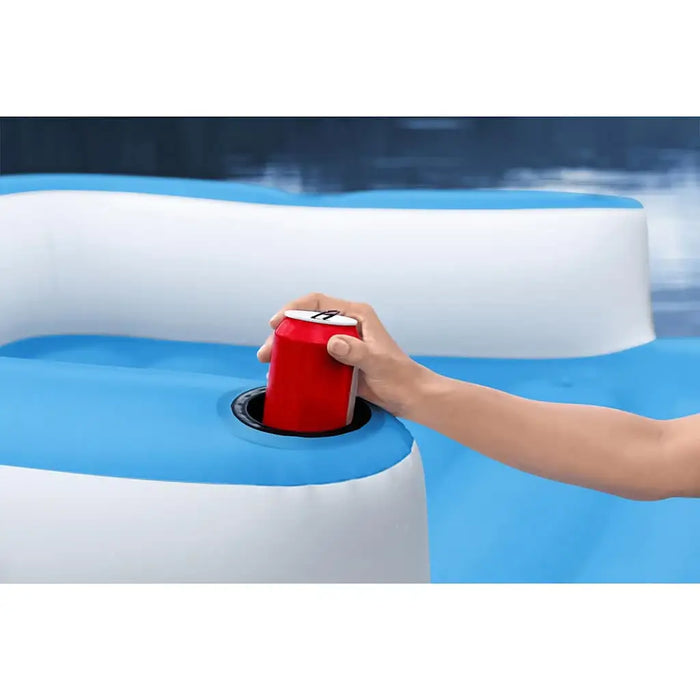 Hand placing red can in cup holder on blue and white inflatable luxury pool lounger
