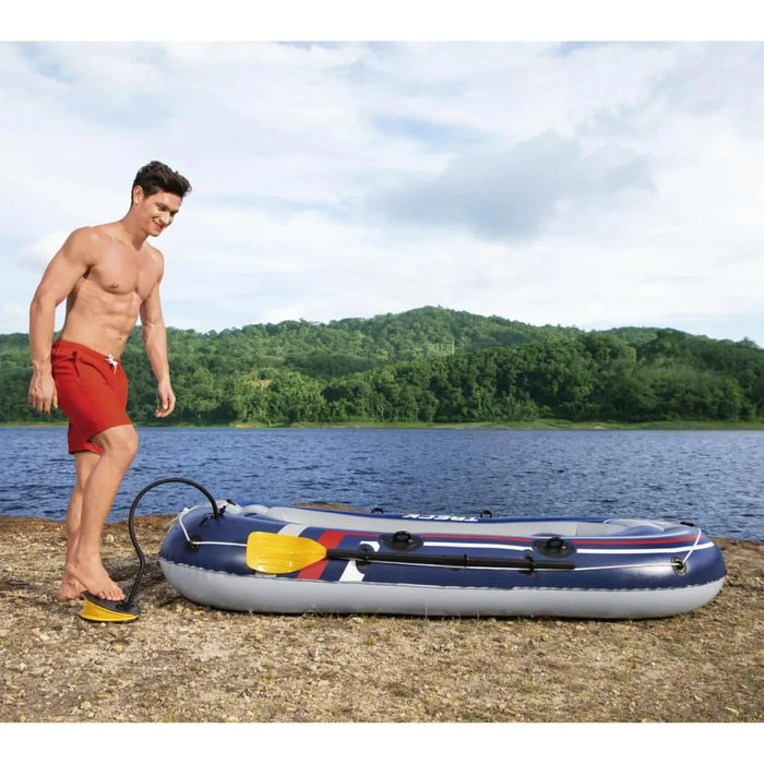 Man inflating Hydro-Force Treck X2 inflatable boat by a lake with forested hills