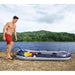 Man inflating Hydro-Force Treck X2 inflatable boat by a lake with forested hills