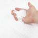 Hand holding and pouring small white polystyrene foam beads on a white background