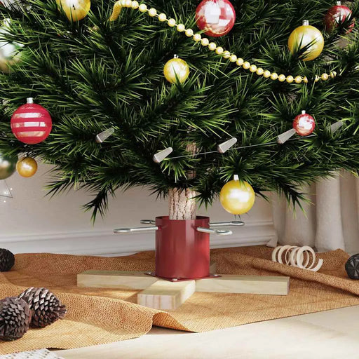 Decorated Christmas tree base with red and gold ornaments, pine cones, and beige fabric on floor