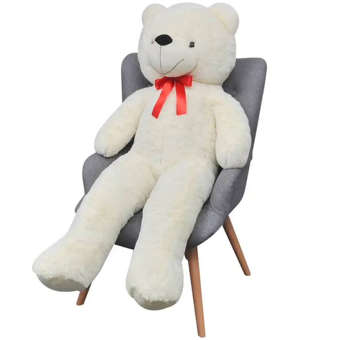 Large white teddy bear with a red bow sitting on a gray chair against a white background