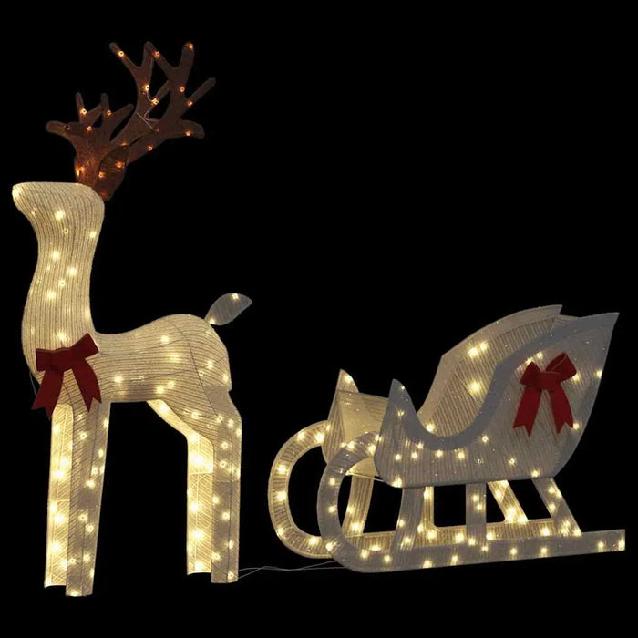 Lit Christmas decoration featuring a reindeer with antlers and a sleigh with red bows on black background