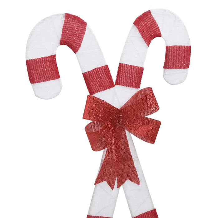 Two white and red striped candy canes crossed with a red glittery bow in the center