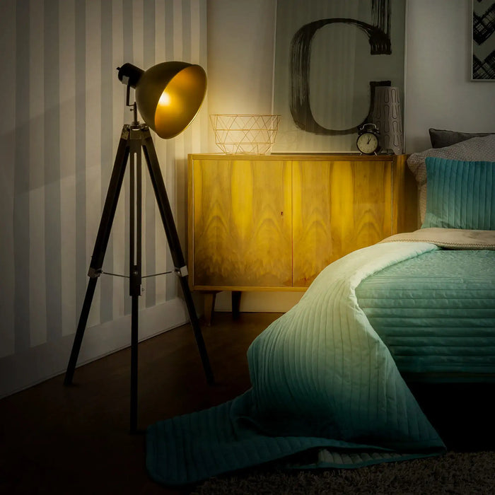 Vintage-style tripod lamp in a bedroom setting with a bed and dresser.