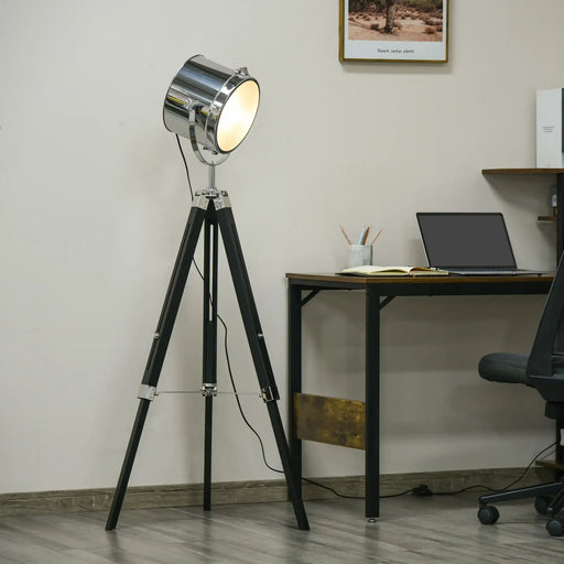 Floor lamp with a tripod design in a room with a desk and laptop.
