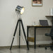 Floor lamp with a tripod design in a room with a desk and laptop.