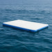 Inflatable floating water deck platform with blue edges on calm ocean water.