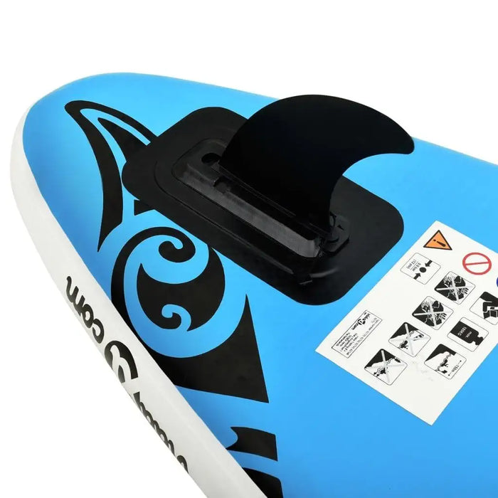 Close-up of blue inflatable SUP board with black fin, tribal graphics, and safety stickers.