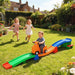 Children playing with a colorful toy track set in a garden.