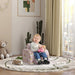 Toddler sitting on pink unicorn-themed chair in a bright nursery with cactus, toy car, and teddy bear