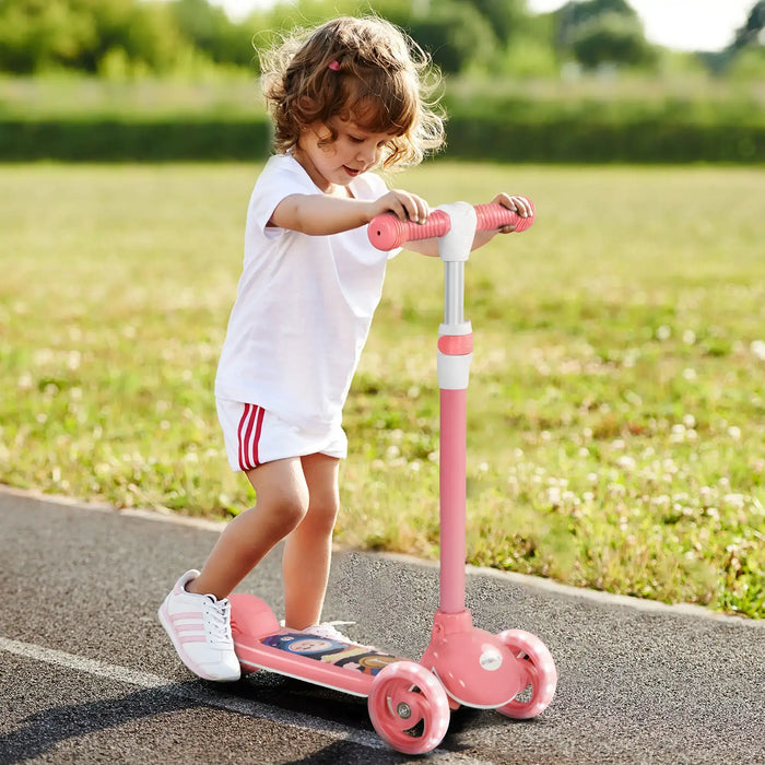 Toddler girl riding pink three-wheeled scooter on paved path in sunny outdoor park