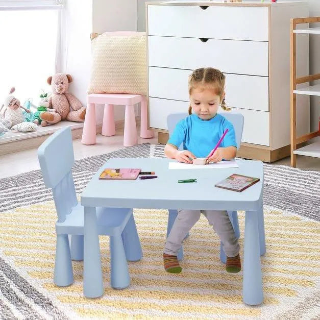 Child drawing at blue kids activity table and chair set in playroom with toys
