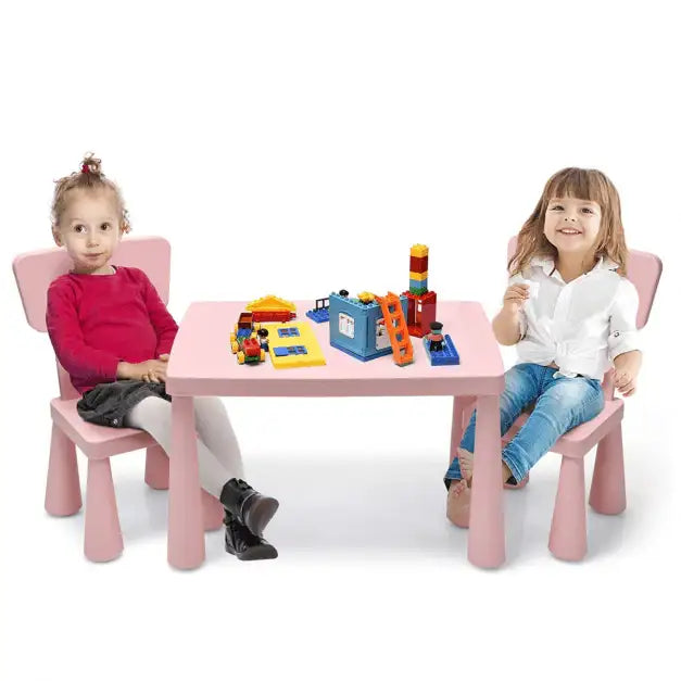Two kids sitting at a pink activity table with chairs, playing with colorful building blocks.