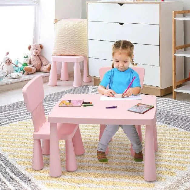 Child drawing at pink kids activity table and chair set in a cozy playroom