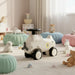 Children's toy car with a steering wheel in a room with colorful cushions and toys