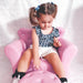 Toddler sitting on a pink kids armchair with crown backrest and crystal button details
