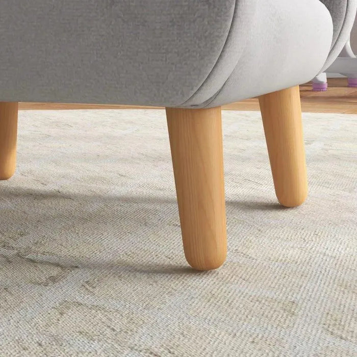 Grey kids armchair with natural wood legs on a light rug, cloud design Dutch velvet