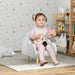 Toddler sitting in grey kids armchair with wooden legs in cozy playroom with plush toys