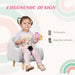 Toddler sitting on grey kids armchair with natural wood legs, ergonomic design, holding snack.