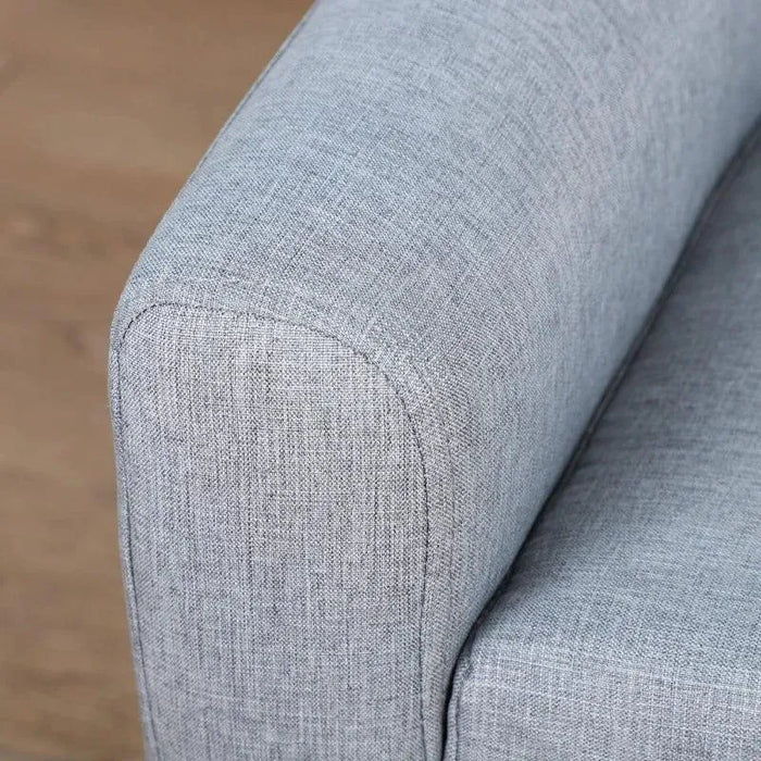 Close-up of grey linen-look armchair armrest with wooden floor background