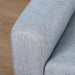 Close-up of grey linen-look armchair armrest with wooden floor background