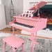 Kids pink 30-key grand piano with matching bench on carpet in cozy living room