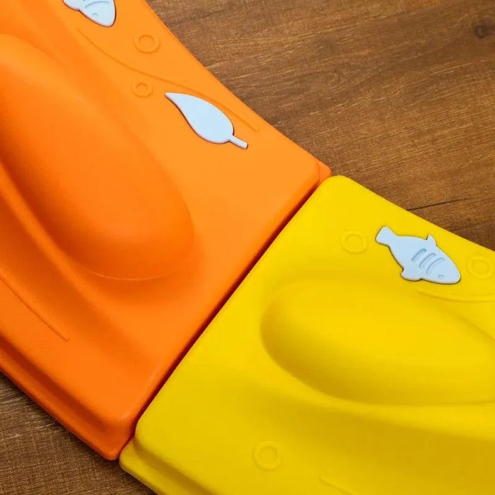 Close-up of kids modular balance beam set, orange and yellow pieces with fish and leaf designs on wood floor.