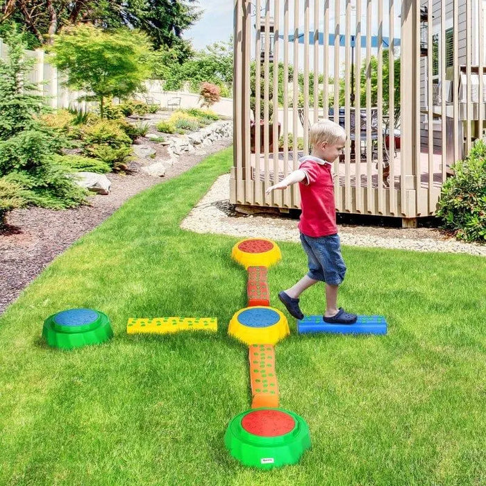 Child balancing on colorful kids' balance beams and stepping stones set in backyard
