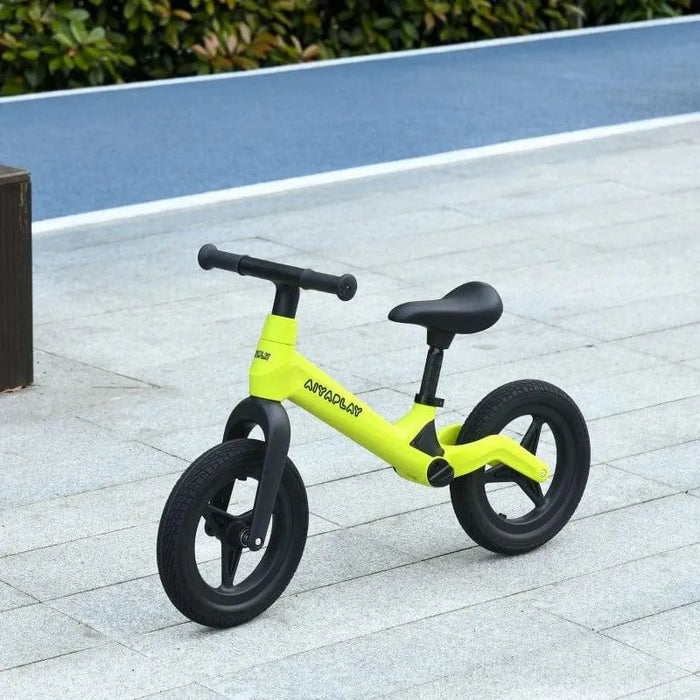 Green and black kids balance bike with adjustable seat and handlebar on pavement