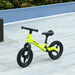 Green and black kids balance bike with adjustable seat and handlebar on pavement