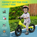 Young boy riding green and black balance bike with helmet outdoors, kids bike features shown.