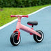 Pink kids' balance bike with adjustable seat and EVA tires on outdoor blue path