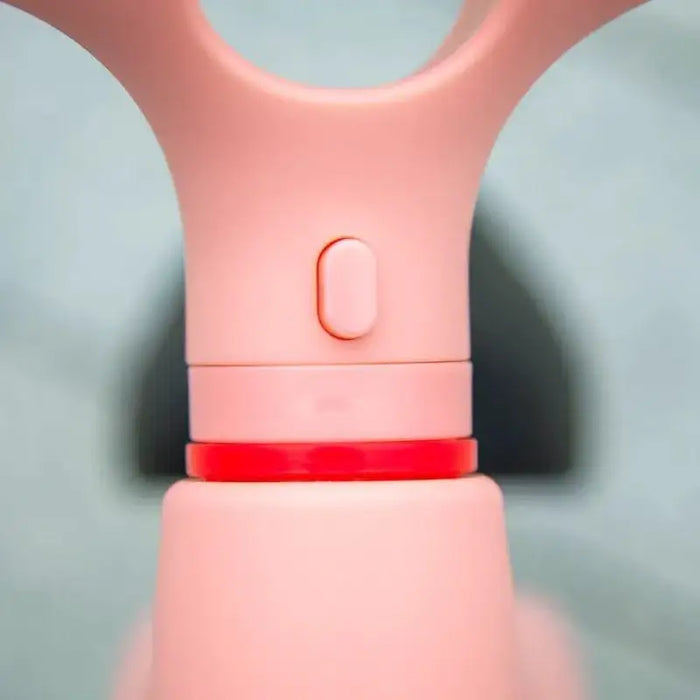 Close-up of pink kids balance bike adjustable seat with red accent detail