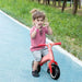 Child riding pink kids balance bike with EVA tyres on blue outdoor path