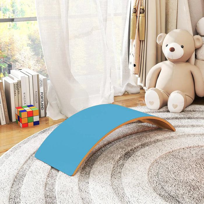 Blue and brown curved object on a textured surface with a teddy bear and books in the background.