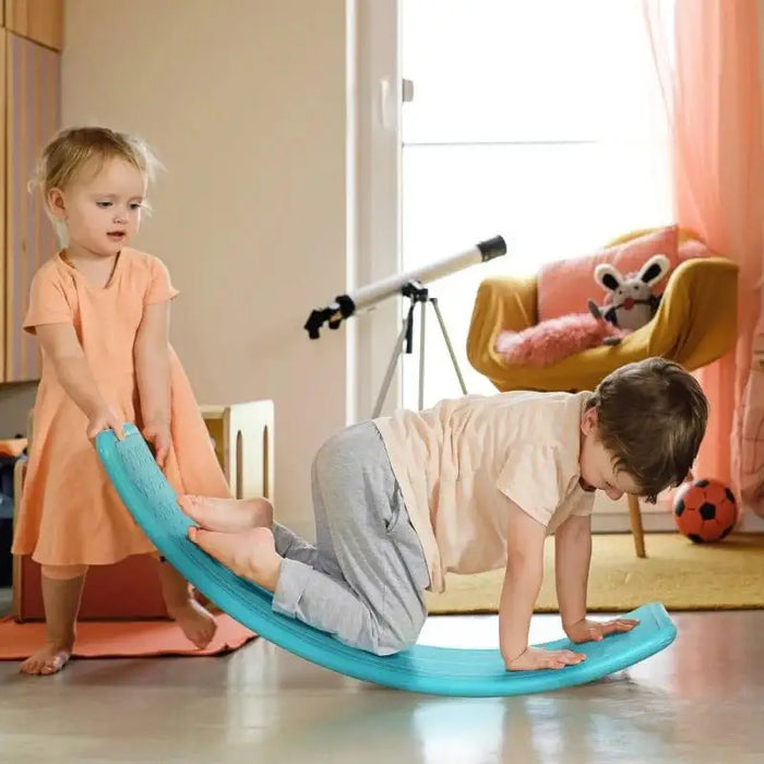 Two kids playing on a blue Montessori balance board in a cozy indoor playroom