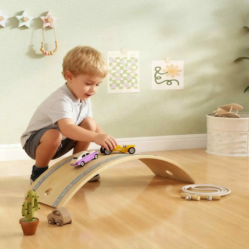 Child playing with a wooden toy track in a room with light green walls and decorative items.