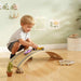 Child playing with a wooden toy track in a room with light green walls and decorative items.