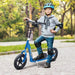 Child with helmet and pads standing on blue big wheel scooter outdoors