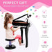 Young girl playing black 37-key mini grand kids piano with stool and microphone, gift idea