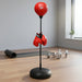 Red boxing speed bag on stand with hanging red gloves, yoga mat, and dumbbells in home gym