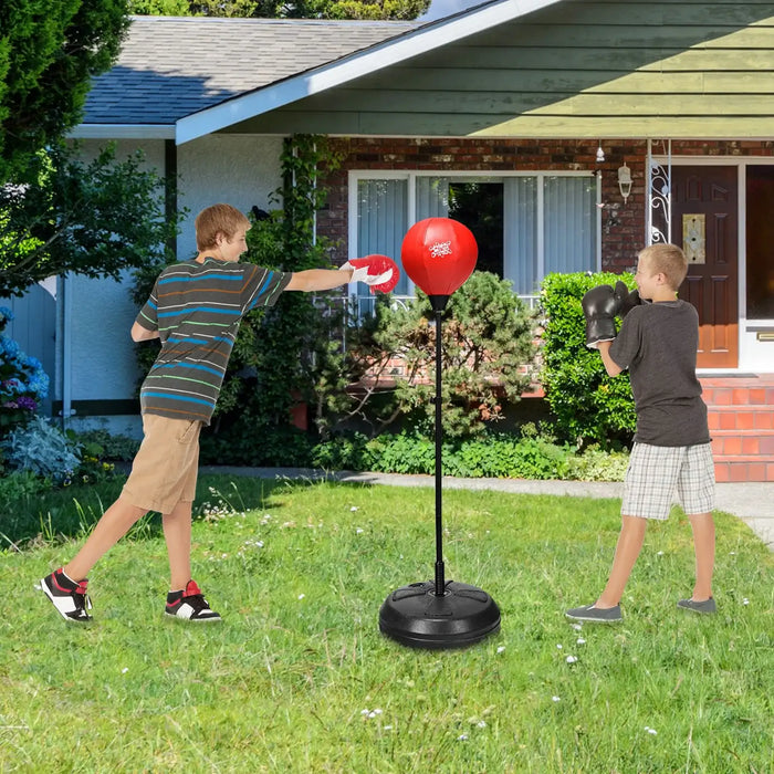 Two boys boxing outdoors with red punching bag on a lawn in front of a brick house