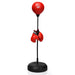 Red boxing gloves hanging on a black adjustable freestanding punching bag with a red speed ball
