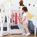 Toddler uses white crown design kids clothes rack with pine wood, mirror, and plush toy.