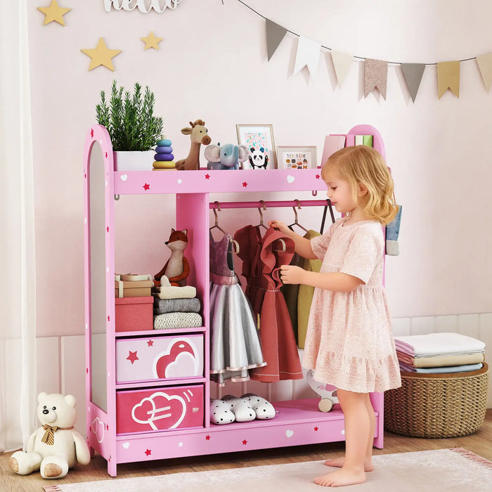 Little girl in pink dress organizing kids clothes on pink storage shelf with mirror and toys