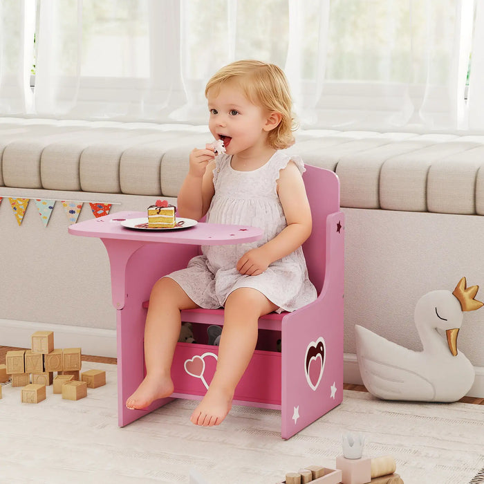 Toddler girl sitting on pink kids desk and chair set with built-in storage, eating cake in playroom