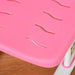 Close-up of pink kids chair with wavy ventilation slits and white legs on wood floor
